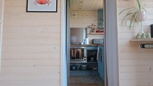A wooden interior with a kitchen area, a framed artwork, and a plant.