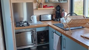 A compact kitchen with wooden cabinets, a gas stove, a microwave, and a sink.