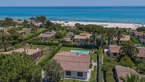 Una zona residenziale costiera con case a tetti in terracotta, una spiaggia e una vista limpida sul mare.