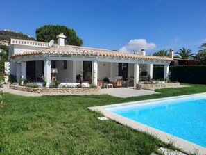 Ein Haus mit Schwimmbad, Sitzgelegenheit im Freien und einem Garten.