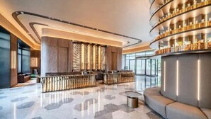 A modern lobby with a central reception desk, a curved seating area, and a display of items on shelves. -  Crystal Orange Shanghai Changfeng  (Shanghai)