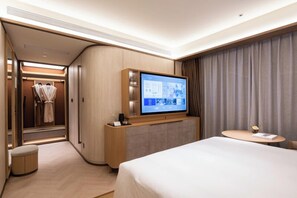 Een hotelkamer met een bed, een televisie, een bureau en een inloopkast.