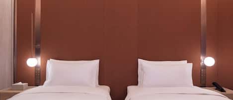 A hotel room with two beds, a nightstand, and a wall-mounted light fixture.