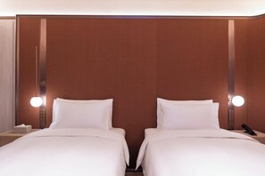 Une chambre d’hôtel avec deux lits, une table de chevet et un luminaire fixé au mur.