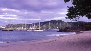 A beach with boats and hills in the background.