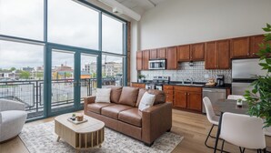 A modern apartment with a large living area, a kitchenette, and a balcony with a city view. - Cozy, Modern Bay Views for Six! (Sandusky)