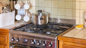Een keuken met een roestvrijstalen fornuis, een pan op de branders, en diverse keukengerei en apparaten.