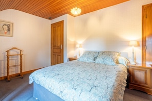 A bedroom with a bed, two bedside tables, a nightstand, a wooden ladder, and a door. - Holiday Home 'Charme Armorine' with Private Garden (Plonéour-Lanvern)