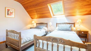 Een slaapkamer met twee houten bedden, een dakraam en bedlampjes.