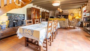 Een eetruimte met een houten tafel en stoelen, een open haard en een stenen muur.