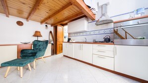 Une cuisine avec des meubles blancs, un plafond en bois et une chaise de couleur turquoise.