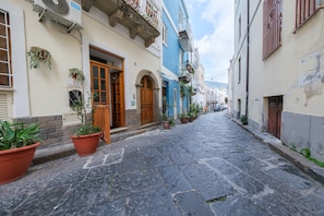 Una estrecha calle adoquinada flanqueada por edificios con arcos y balcones.