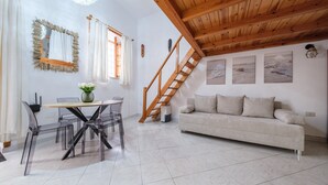 Un salon moderne avec un escalier en bois, un canapé, une table à manger avec des chaises et des œuvres d’art accrochées aux murs.