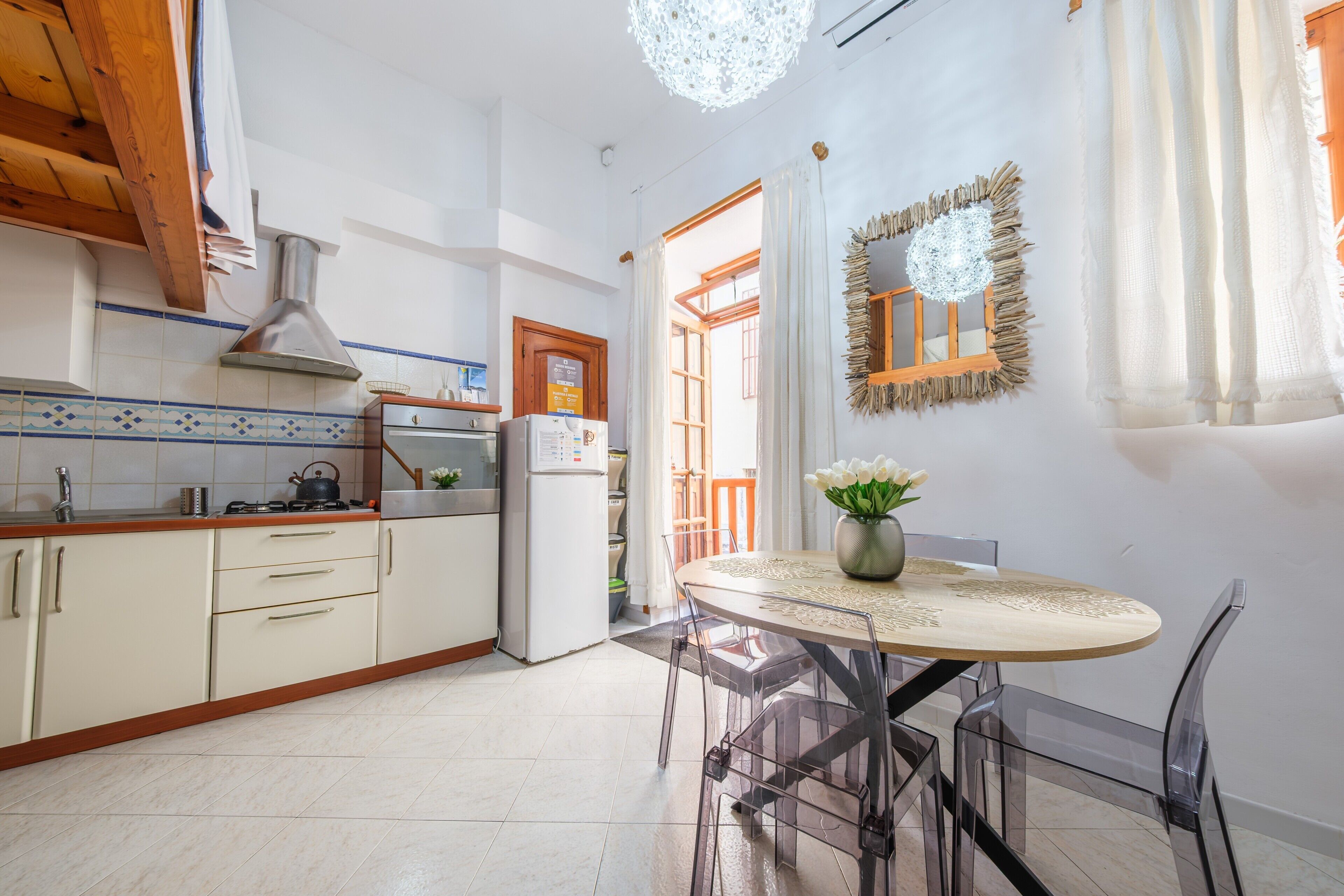 Une cuisine équipée d’une cuisinière, d’un évier et d’un réfrigérateur, une table à manger avec des chaises et un miroir décoratif.