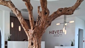 En receptionsdisk med en stor träskulptur formad som ett träd, placerad i mitten av en modern hotellobby.