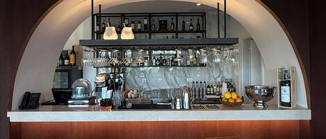 A bar area with a curved counter, bar stools, and a wine display.