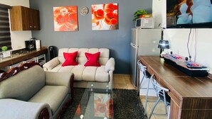 Un salon moderne avec un canapé, une table basse et un téléviseur à écran plat fixé au mur.