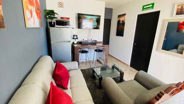 Un salon comprenant deux canapés, une table basse et un coin cuisine équipé d’un réfrigérateur, d’un four à micro-ondes et d’un téléviseur.