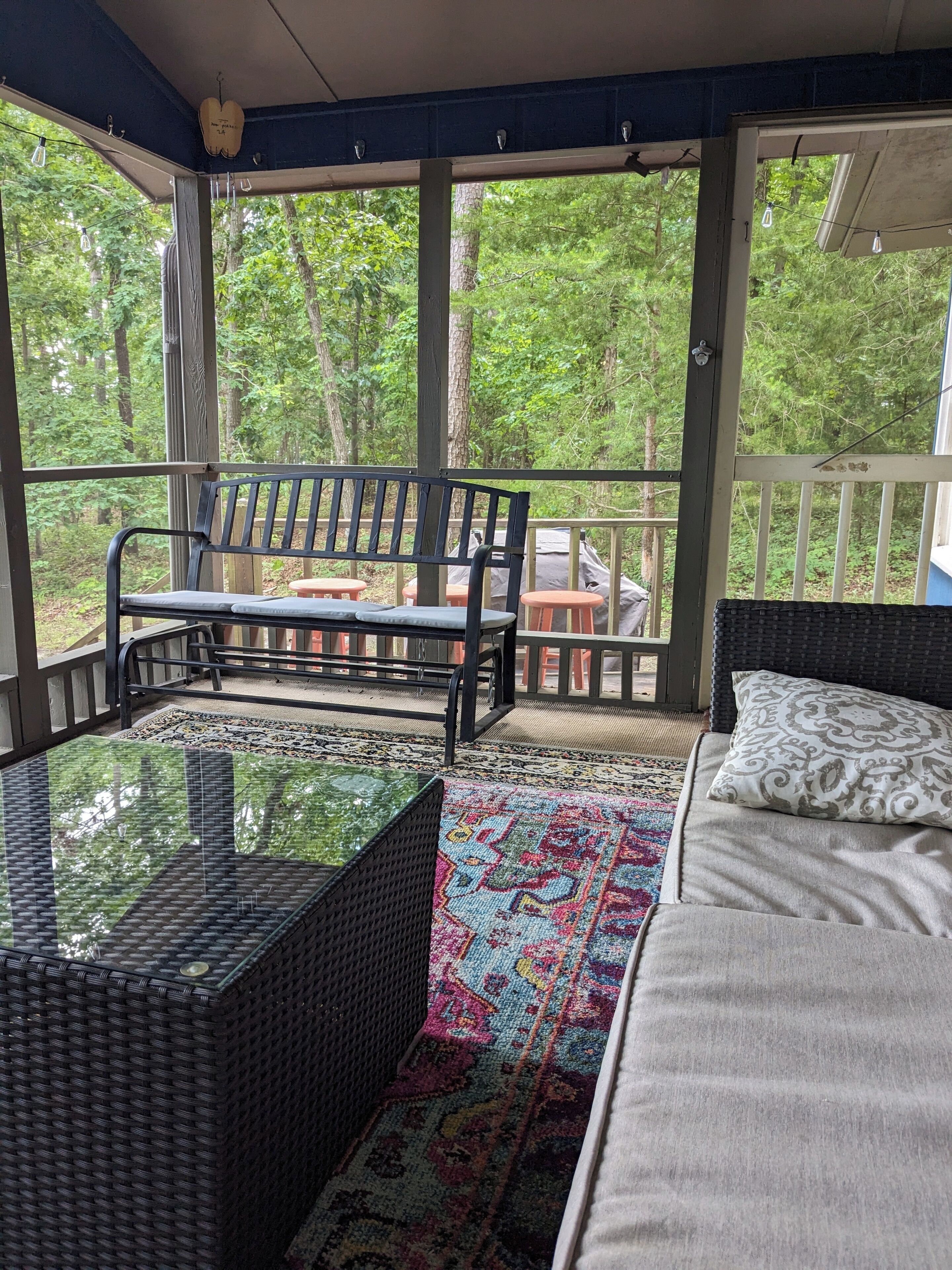 A covered outdoor seating area with a bench, a table, and a sofa.
