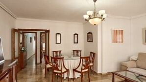A dining area with a round table, chairs, a chandelier, and a sofa.