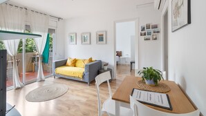 A modern interior with a dining area, a sofa with yellow cushions, and a potted plant on a table. - Apartment 'Fantastic Beach' with Balcony, Wi-Fi and Air Conditioning (Alella)