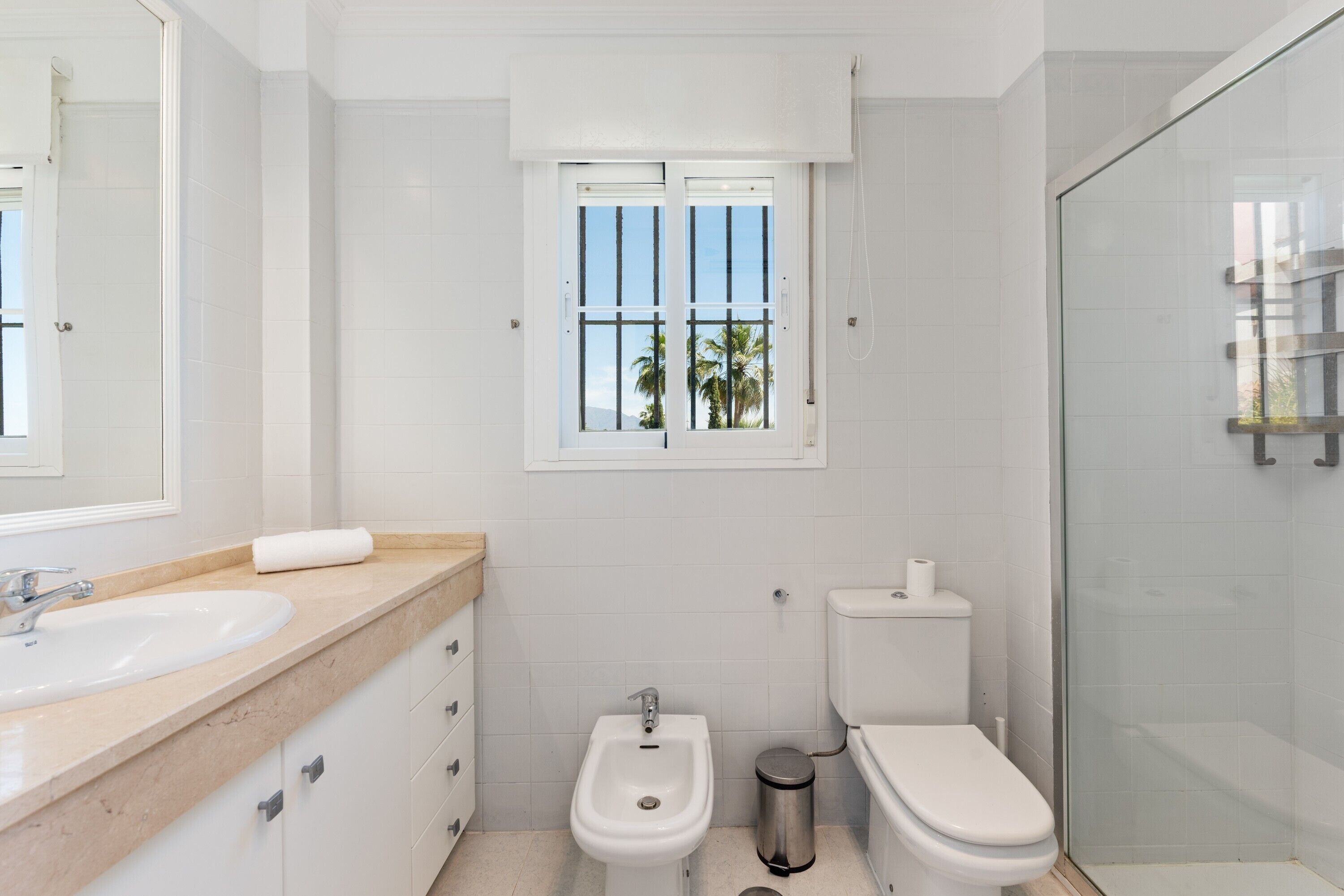 A modern bathroom with a sink, bidet, toilet, and a glass shower enclosure.