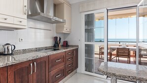 A kitchen with wooden cabinets, a stainless steel range hood, and a granite countertop. - Apartment 'Panoramic Sea Views' with Sea View, Wi-Fi and Air Conditioning (Manilva)