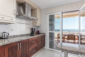 A kitchen with wooden cabinets, a stainless steel range hood, and a granite countertop. - Apartment 'Panoramic Sea Views' with Sea View, Wi-Fi and Air Conditioning (Manilva)