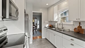 A modern kitchen with white cabinetry, a stainless steel sink, and a built-in microwave.
