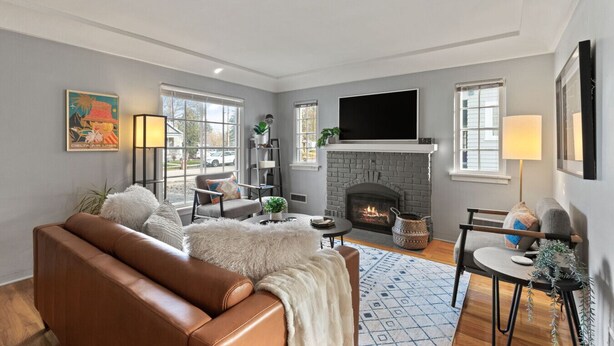 A living room with a fireplace, leather sofa, and a flat-screen TV.