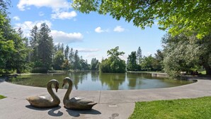 A park with a pond, swan sculptures, and surrounding trees.