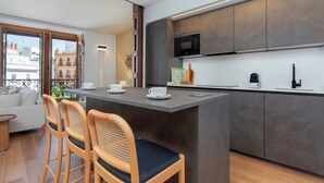 A modern kitchen with a central island, bar stools, a microwave, and a coffee machine. - Genteel Home Tomás de Ibarra IV (Seville)