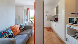 A modern kitchen with white cabinets, a microwave, and a dining area with a table and chairs. - Vacation Home 'Mare Nostrum' with Mountain View, Private Terrace, and Air Conditioning (Castelsardo)