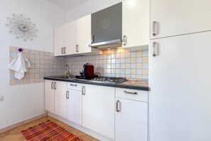 A modern kitchen with white cabinets, a gas stove, and a decorative clock on the wall.