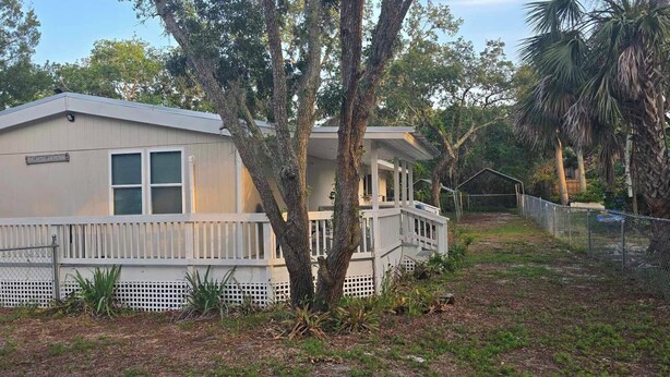 A single-story house with a front porch, a fenced yard, and a mailbox. - Clambassador Cottage (Cedar Key)
