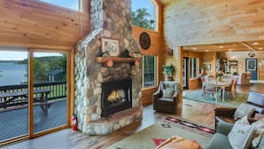 A spacious cabin with a stone fireplace, wooden deck, and a view of a lake. - County Highway - Trail Access, Lake Access, Sleeps 23 (Minong)