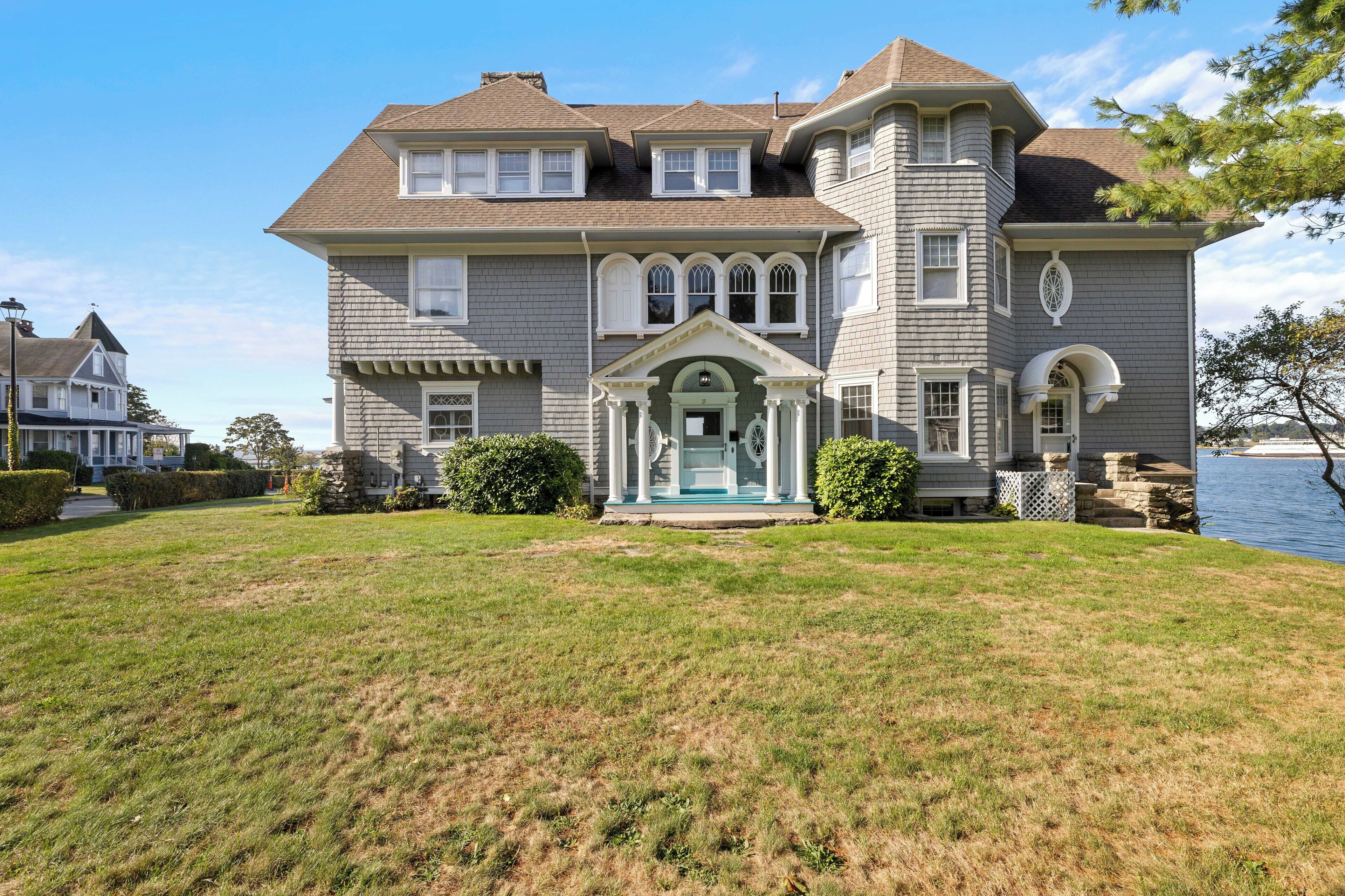 A large, two-story house with a prominent porch and a small fountain.