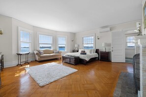 Een ruime slaapkamer met een groot bed, een bank en een open haard.