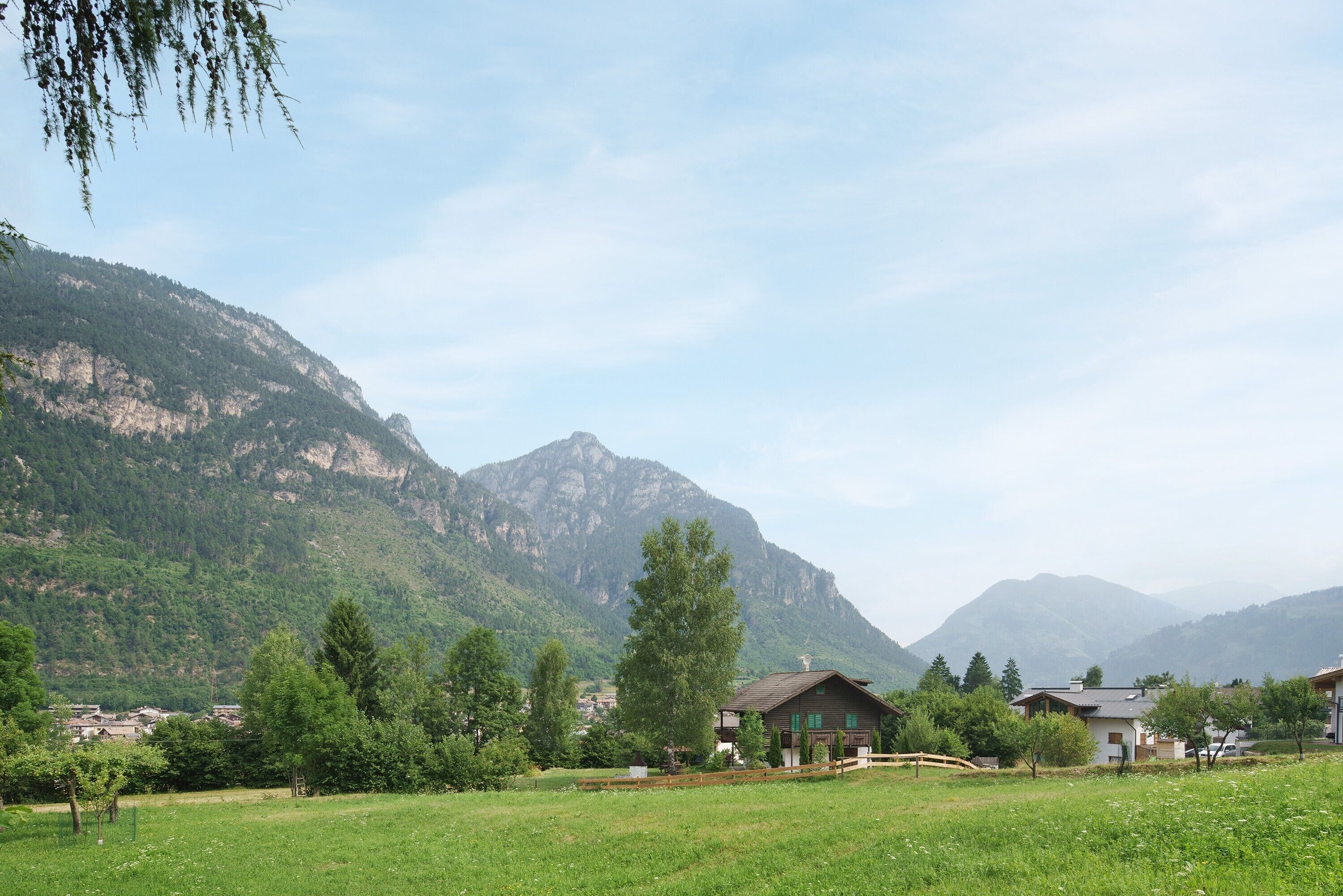 Ein ländliches Bergdorf mit Häusern, einem Feld und Bergen im Hintergrund.
