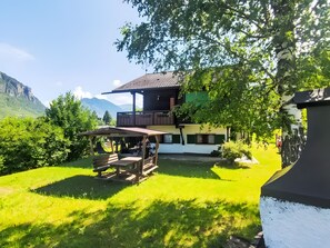 Una cabaña con terraza de madera y vistas a las montañas.