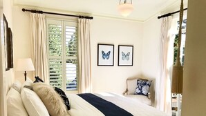 A bedroom with a bed, a nightstand, a lamp, a chair, and two butterfly wall art pieces.