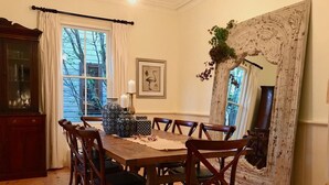 A dining room with a wooden table and chairs, a cabinet, and a large mirror.