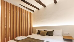 Een moderne hotelkamer met een groot bed, houten latten aan de muur en een nachtkastje.