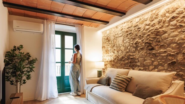 Een knusse woonkamer met een stenen muur, een houten plafond en een groene deur.
