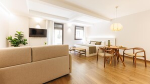 Un salon moderne comprenant un canapé, une table à manger, des chaises et un téléviseur fixé au mur.