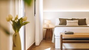 Une chambre d’hôtel avec un lit, une table de chevet, une lampe et un banc.