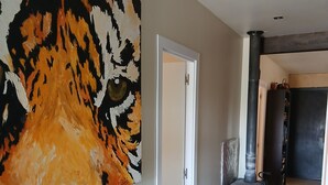 Un passadís amb un gran quadre abstracte a l'esquerra, una porta blanca i una estufa negra al fons.
