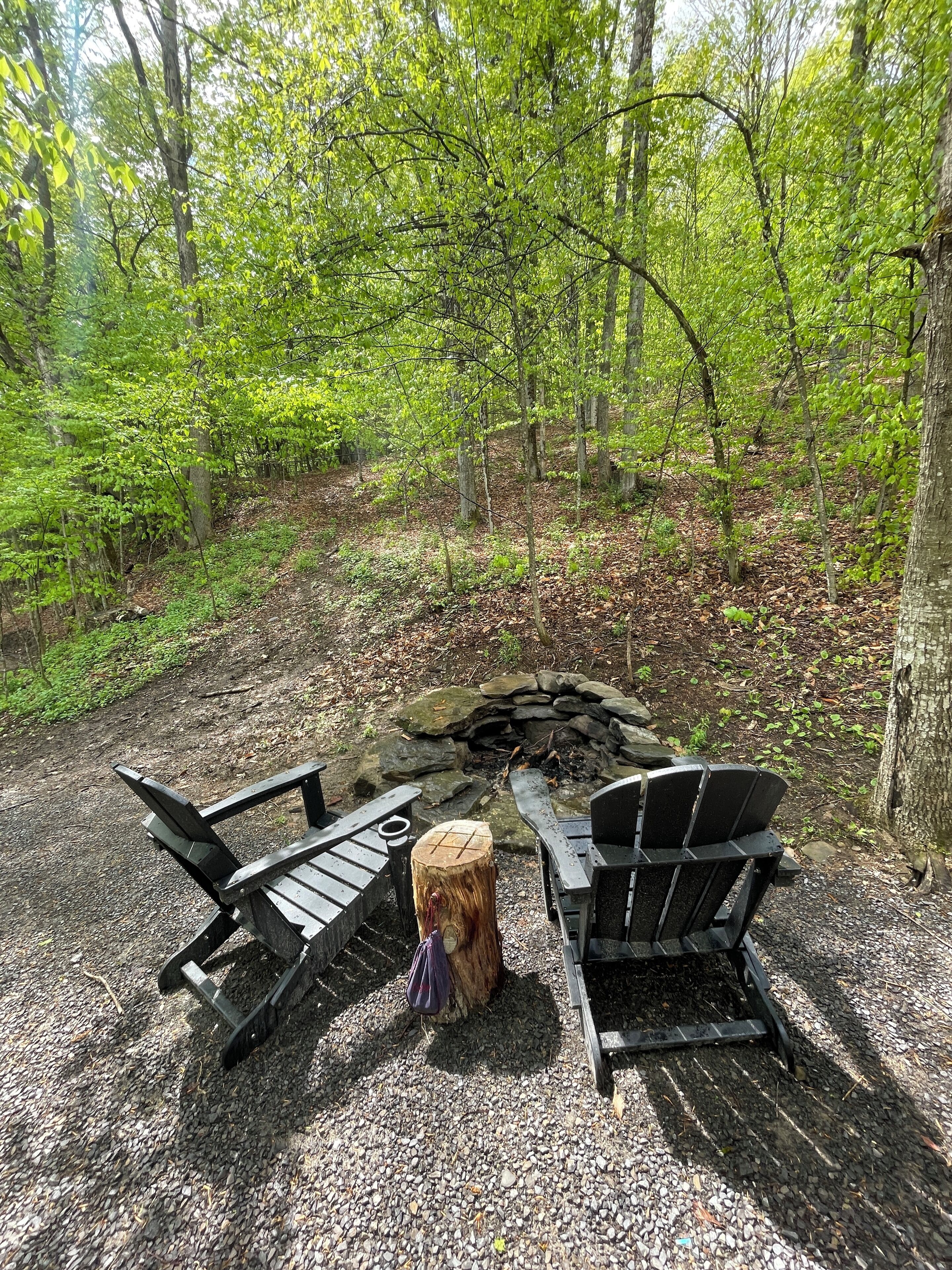 Un campeggio con due poltrone Adirondack, un braciere e un ceppo di pietra.