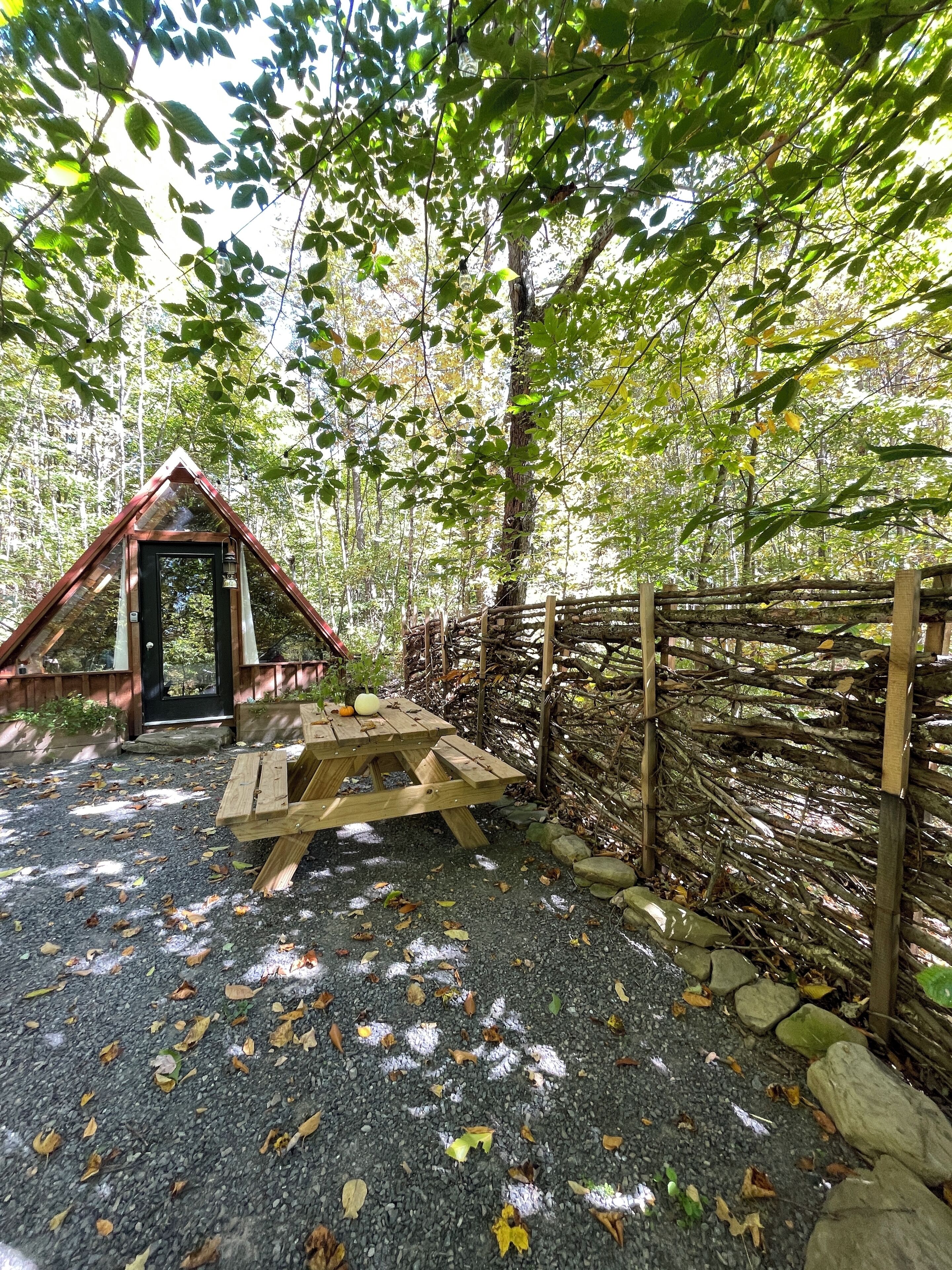 Eine rustikale Holzhütte mit Satteldach, Picknicktisch und Holzzaun.