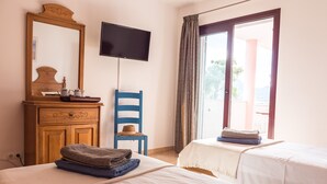Ein Hotelzimmer mit Bett, Fernseher, einem Holzschrank und einem Sessel.